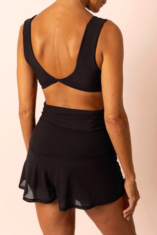Back view of mature woman wearing black swim top with matching high-waist swim skort skirt