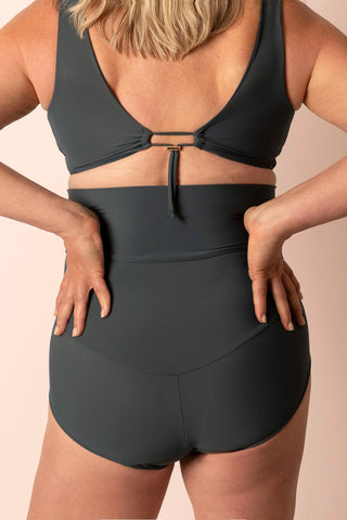 Person wearing a black bikini set on a beige background