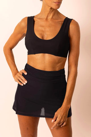 Mature woman wearing black swim top with matching high-waist swim skort skirt