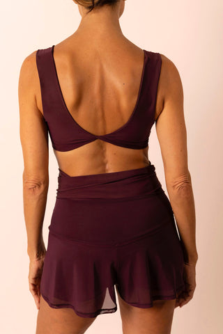 Back view of mature woman wearing a burgundy swim top and matching high-waist swim skirt skort