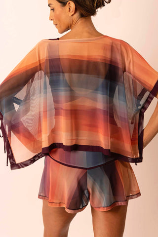 Back view of mature woman wearing a burgundy, peach and blue stripe print flowy rectangle top with matching swim skirt skort.