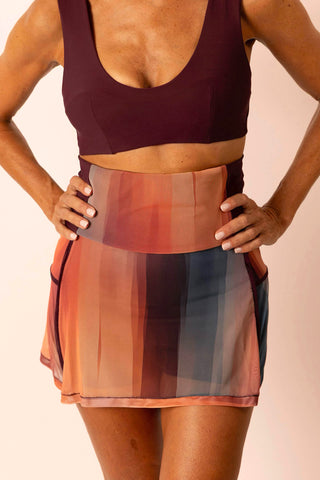 Mature woman wearing a burgundy swim top with matching painted stripe printed swim skirt skort.