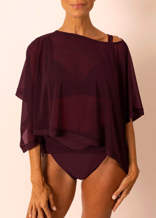 Mature woman wearing a sheer flowy burgundy top and matching swimsuit