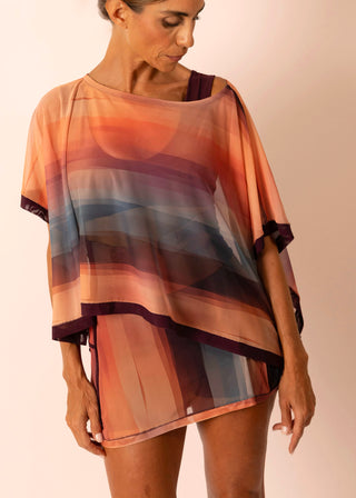 Mature woman wearing a sheer flowy blue sunset striped and matching swimsuit