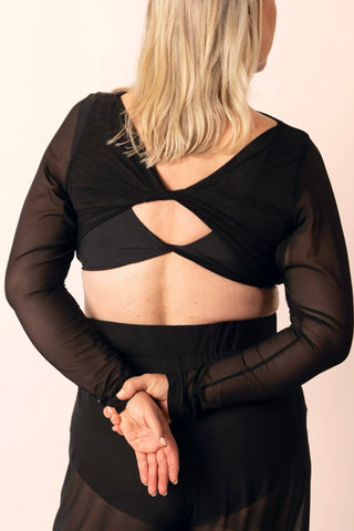 Reversible black long-sleeve twist top with sheer sleeves worn by a mature woman