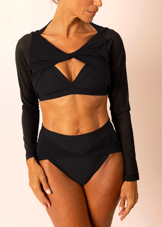 Reversible black long-sleeve twist top with sheer sleeves worn by a mature woman