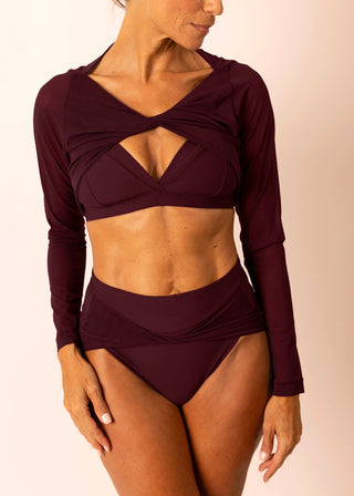 Reversible burgundy long-sleeve twist top with sheer sleeves worn by a mature woman