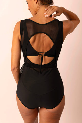 Back view of mature woman wearing a black wrap top one piece swimsuit with matching custom swim bra