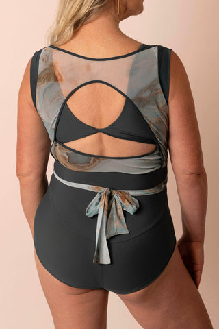 Back view of larger mature woman wearing a light teal & tan marble printed wrap top one piece swimsuit with matching custom swim top