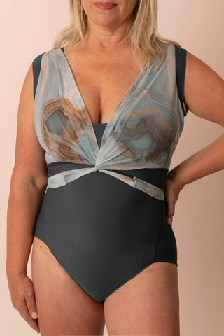 Larger mature woman wearing a light teal & tan marble printed wrap top one piece swimsuit with matching custom swim top
