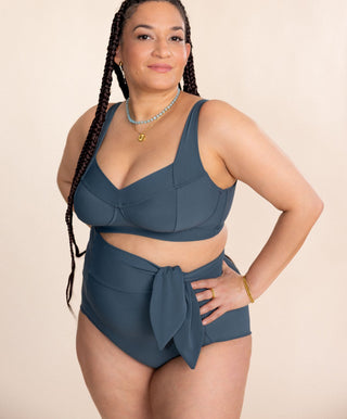 Woman wearing a blue swimsuit with a beige background