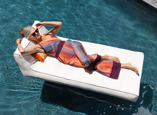 A mature woman lounging on a pool float in a pool
