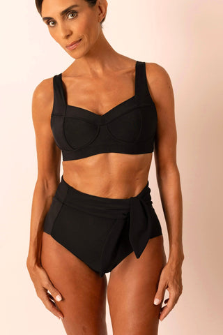 Woman wearing a black bikini set against a beige background